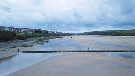 Man-Crossing-Bridge-Across-Gannel-River-In-Newquay-United-Kingdom---Wide-shot