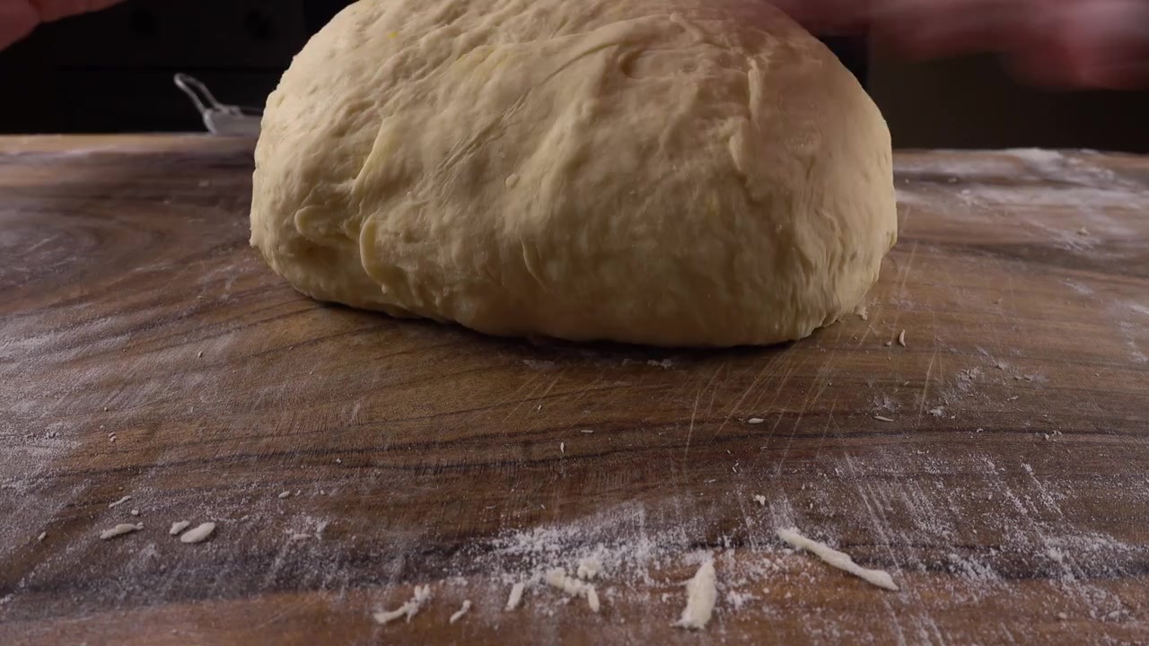 Kneading dough on a wooden board with your hands.
