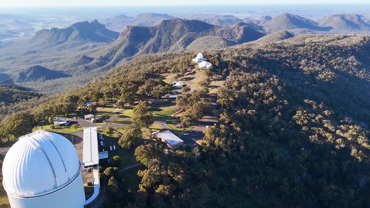 Ripresa con drone di cupole di telescopi su una cresta montuosa nel Parco Nazionale di Warrumbungle, Australia