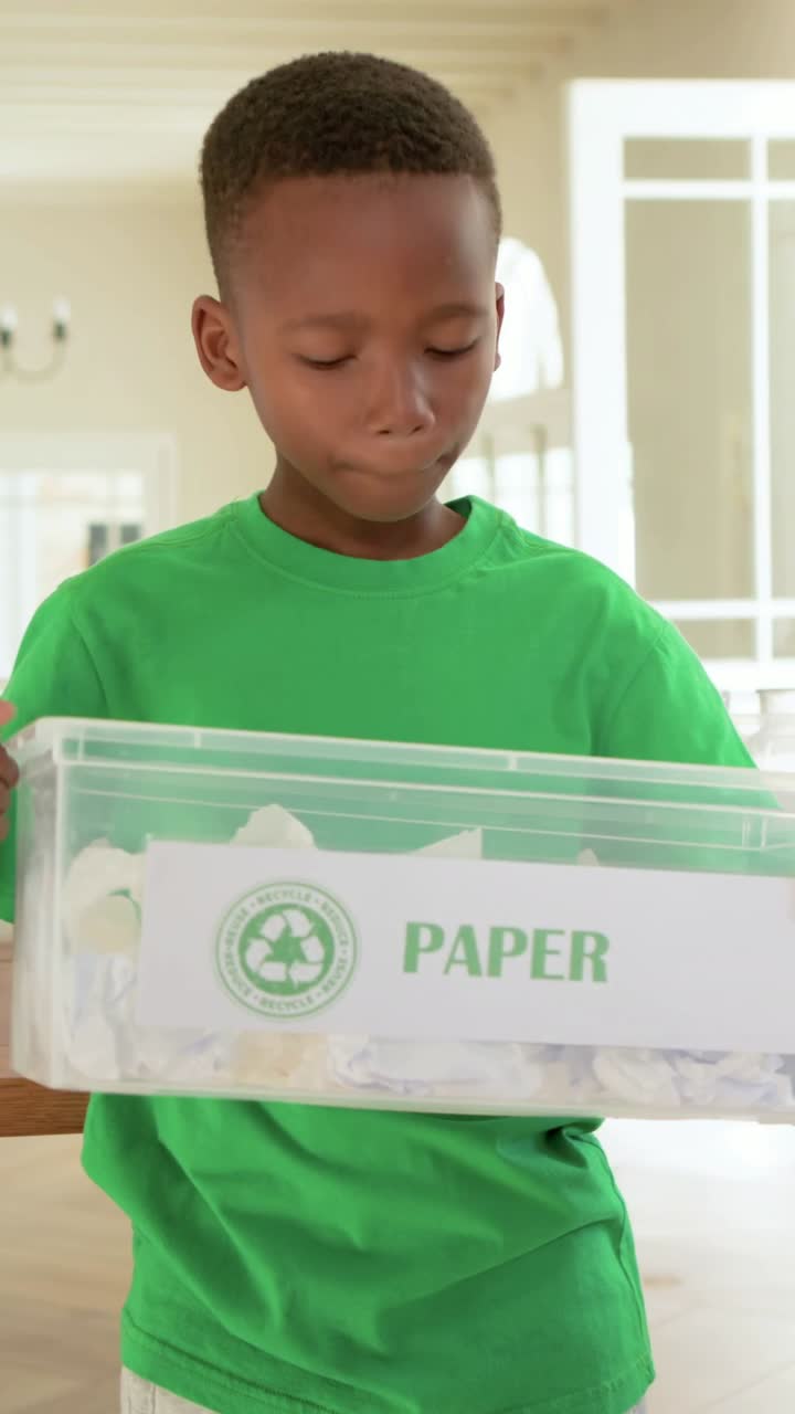 Vertical video: Looking down at bin, boy in green tee adjusting grip at home, presenting PAPER bin