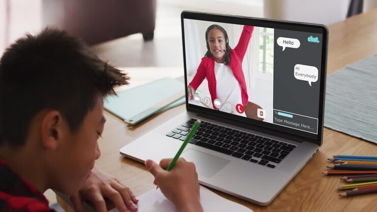 Scolaro che usa il laptop per una lezione online a casa, con un suo compagno e una webchat sullo schermo