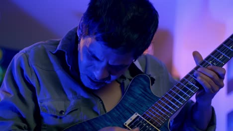 slow motion shot of musician playing guitar, nodding his head with passion