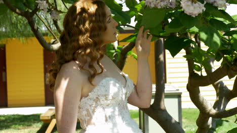 novia pelirroja mirando flores en un árbol