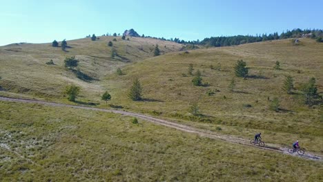 couple enjoying weekend cycling on countryside dirt road in slovenia - aerial drone view