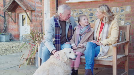 grandparents with granddaughter and pet dog outside house getting ready to go for winter walk