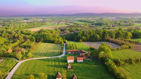 Volando-Con-Drones-Alrededor-Del-Antiguo-Pueblo-Cerca-De-Las-Montañas-A-Lo-Lejos,-Hermoso-Cielo-Púrpura-Y-Azul-Con-Iluminación-Natural-Mezclada-Con-Los-Colores-Del-Cielo