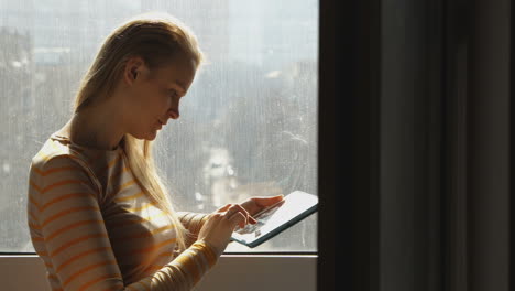 mujer con computadora portátil junto a la ventana