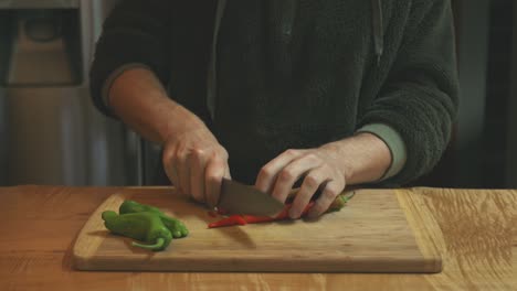 cooker chopping red and green hot chili pepper in the kitchen food cutting board