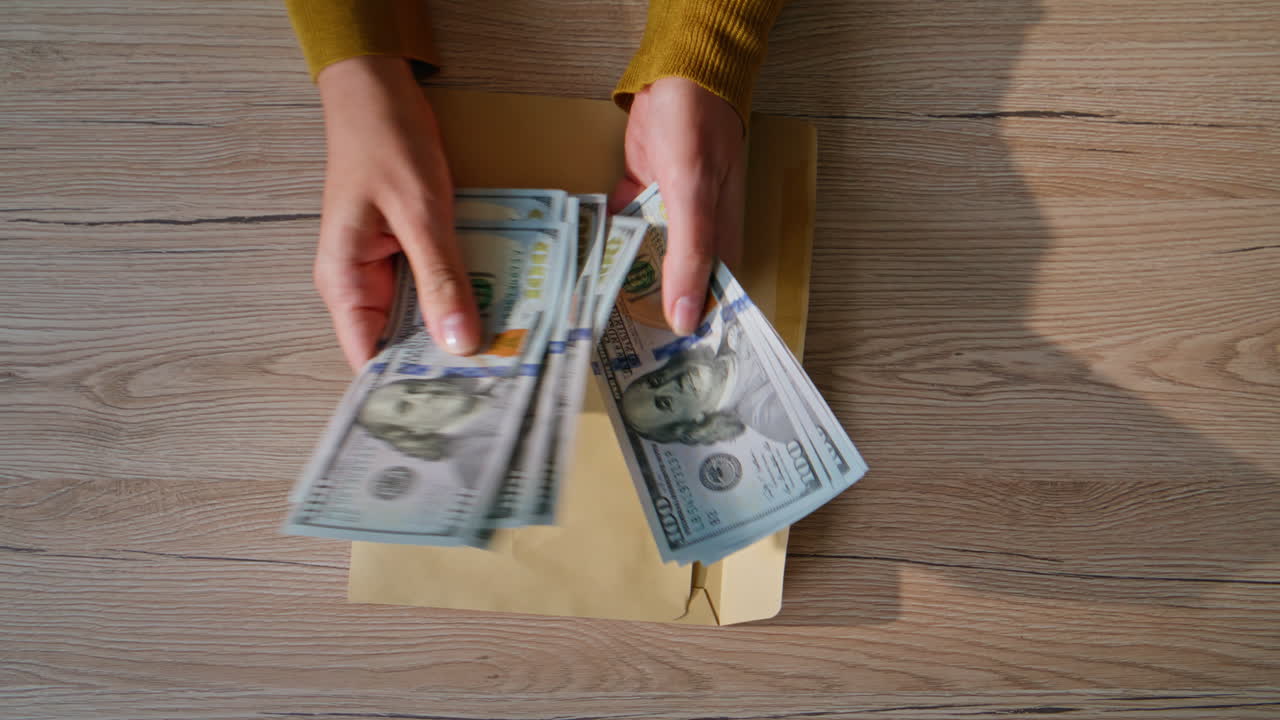 Businesswoman hands counting bills US dollar at office desk closeup top view