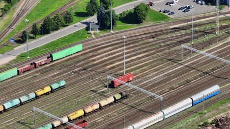 a red cargo wagon without a locomotive moves on the tracks at a train station