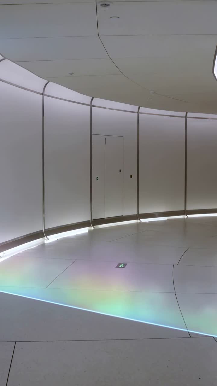 Video vertical: La cámara se desplaza revelando una pared curva con puerta de servicio, parche de arcoíris en el pasillo.
