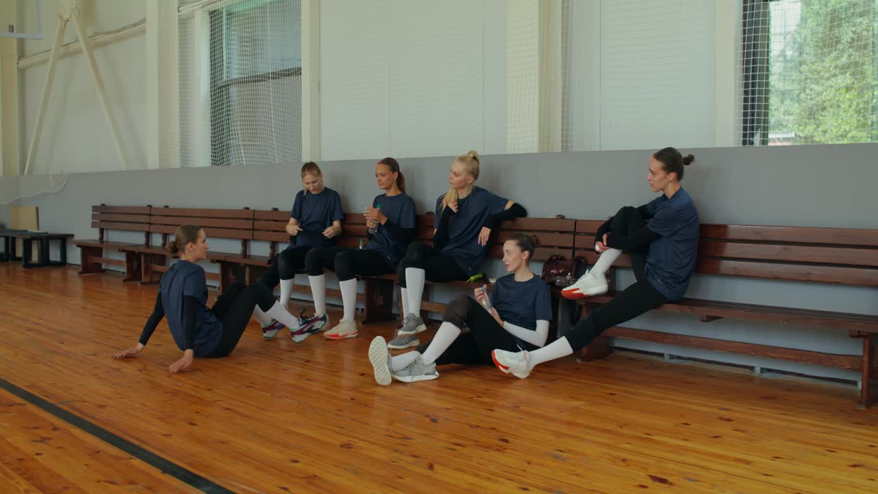Volleyball team resting on a bench in a gym