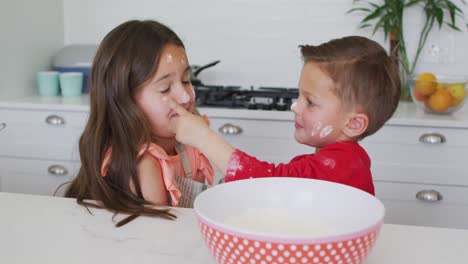 hermana y hermano caucásicos felices jugando juntos con masa en la cocina