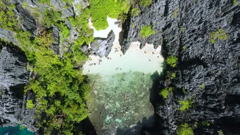 vista aérea: turistas nadando en la playa secreta, una laguna tropical poco profunda rodeada de acantilados cársticos