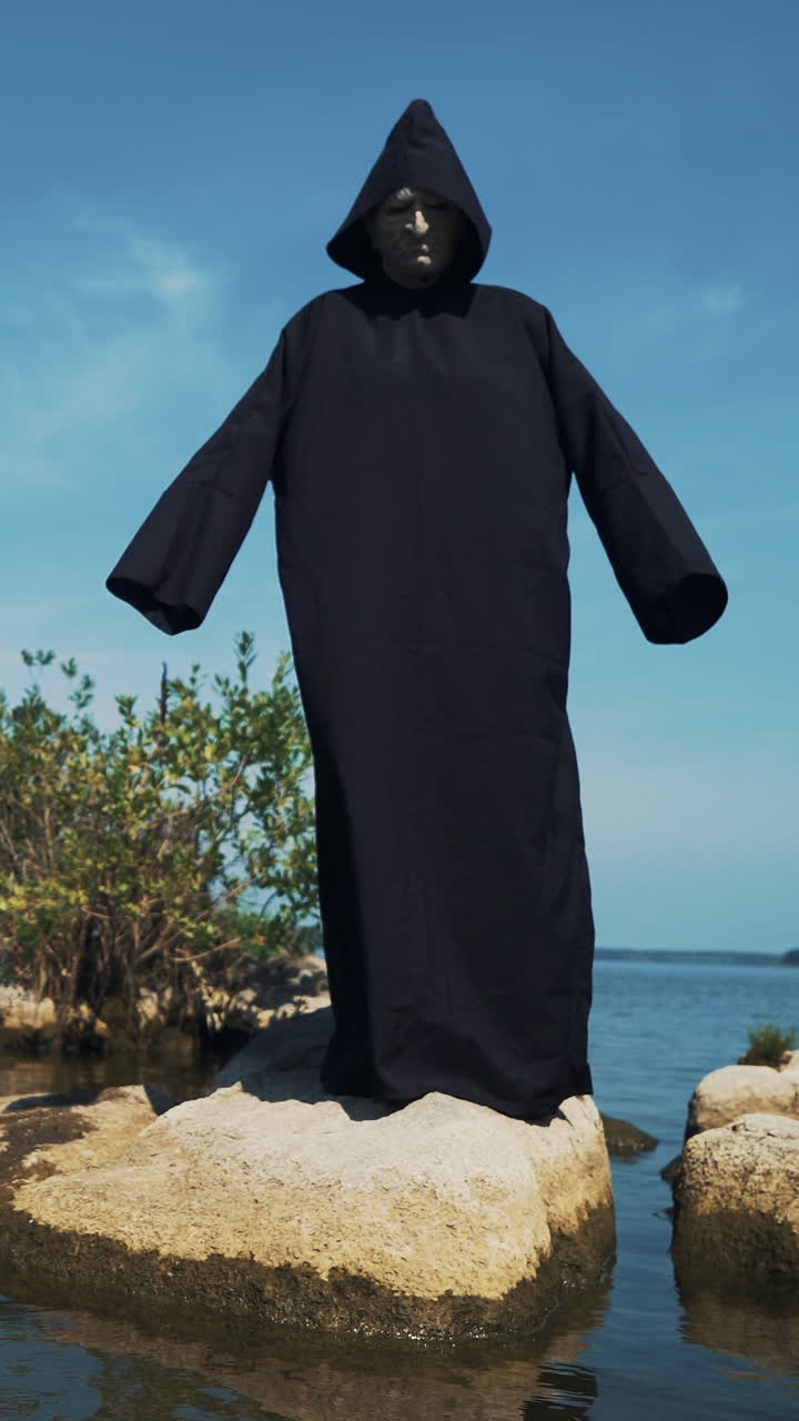 Eerie witch on river bank watches the camera. Vertical video