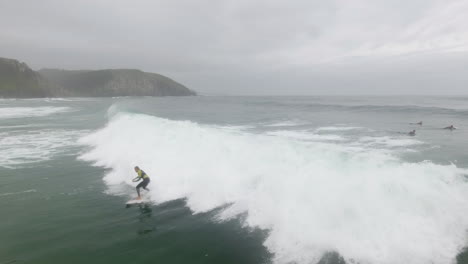 cinemática de acción aérea sobrevolando a los surfistas surfeando en coffee bay en sudáfrica