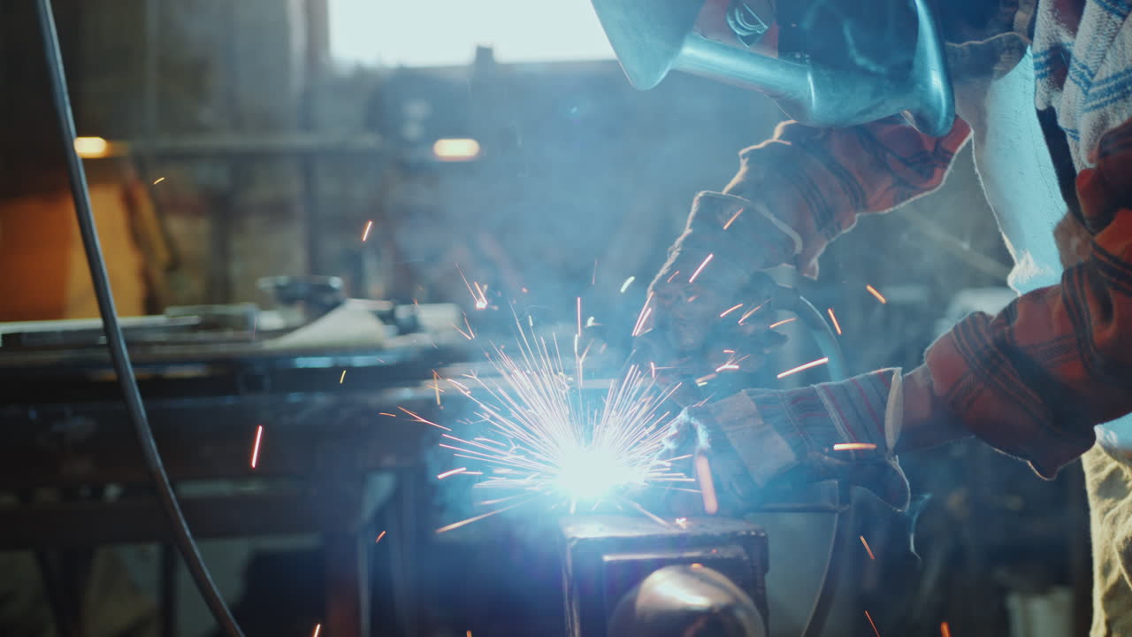 Industrial Worker in Protective Uniform Welding Iron in the Workshop