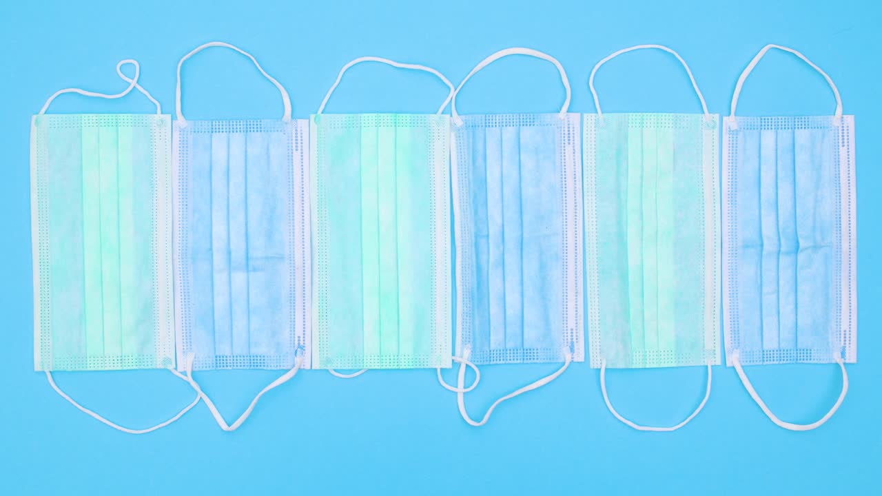 Blue and green medical masks for prevention covid-19 appear on blue theme. Stop motion