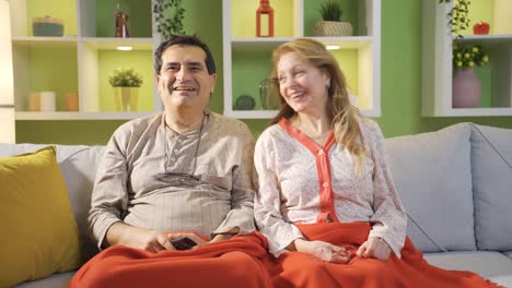 happy couple watching tv together at home.