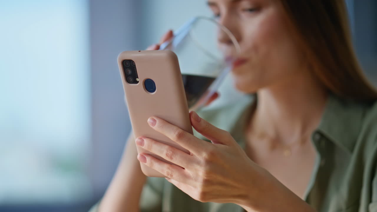 Signora rilassata che guarda il cellulare mentre beve un caffè in un'atmosfera casalinga, primo piano