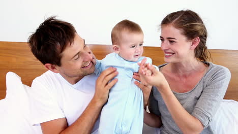 Happy-parents-lying-on-bed-with-baby-son