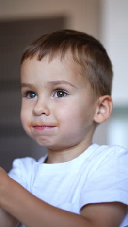 beautiful caucasian kid with moustache from a drink. cute toddler chews his food and claps his hands. close up. vertical video.