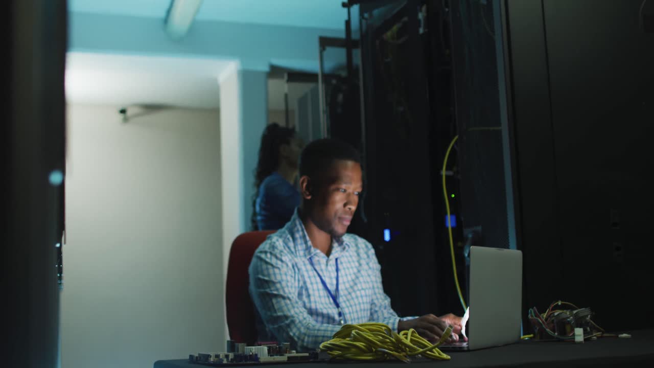 técnico de computadoras afroamericano trabajando en una sala de servidores de negocios.