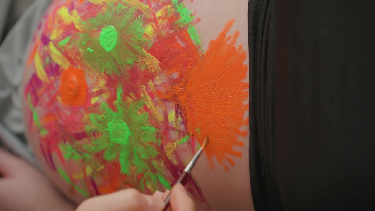 Primo piano di un pancione dipinto con vivaci colori neon