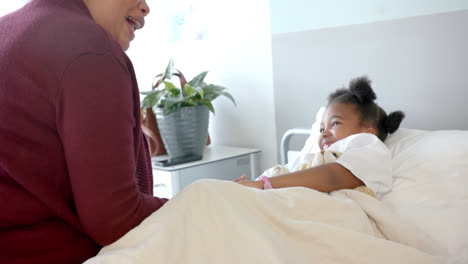 Feliz-Madre-Afroamericana-Engañando-Con-Su-Hija-Acostada-En-La-Cama-Del-Hospital-Con-Mascota,-Cámara-Lenta