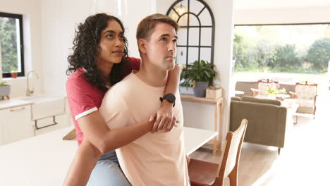 young multiracial couple embracing in kitchen, enjoying time together at home