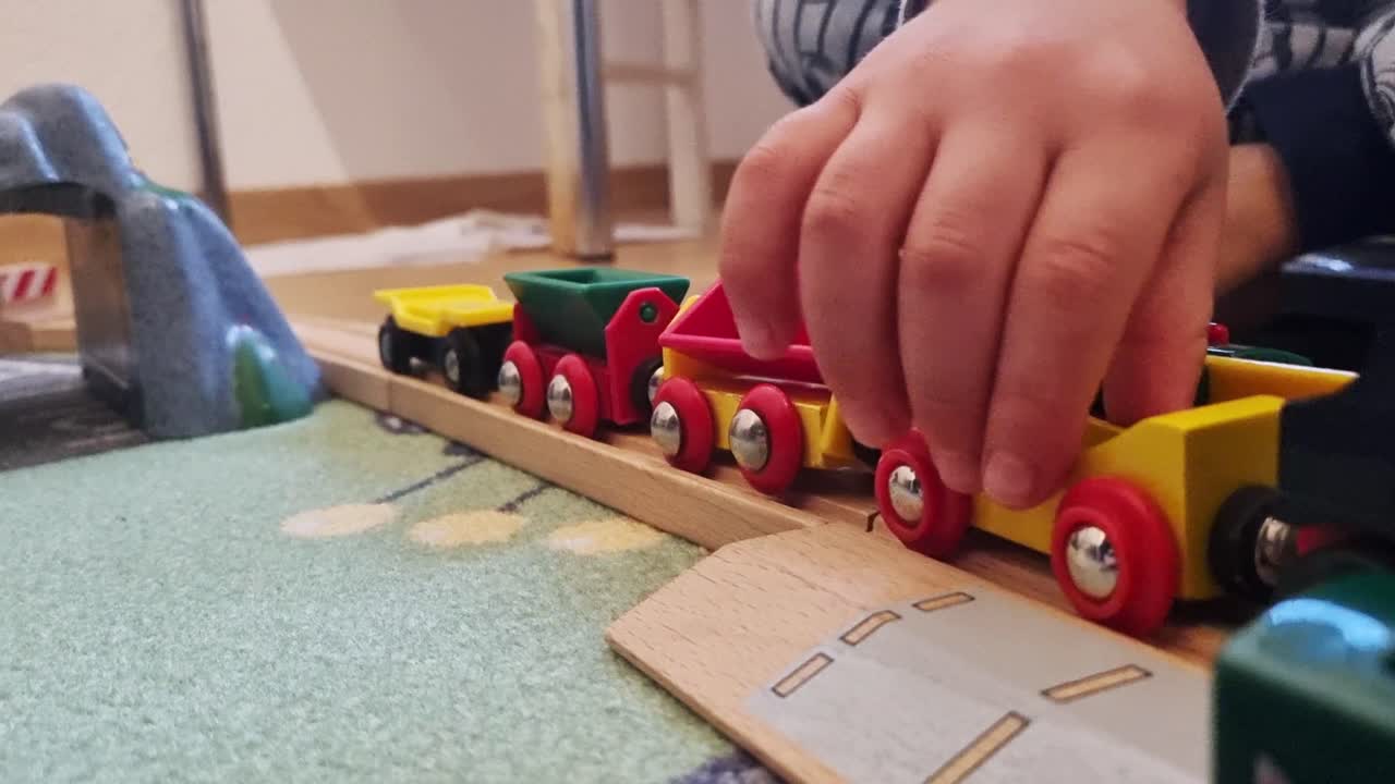 niño pequeño jugando con un tren de madera en un carril de tren de madera, moviendo el tren hacia adelante y hacia atrás