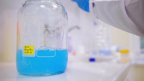 А-scientist-pours-a-liquid-into-a-large-jar