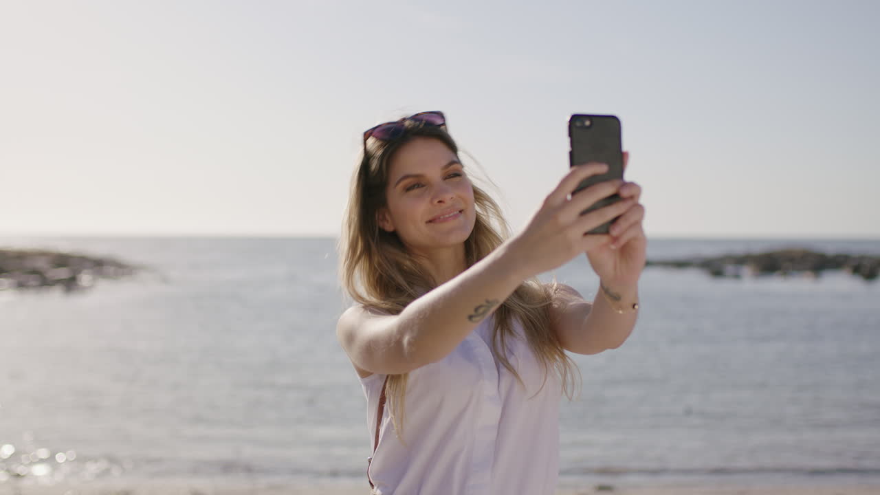 retrato de una hermosa mujer rubia tomando una selfie en la playa usando el teléfono sonriendo feliz