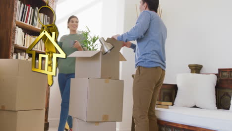 animation of gold house key and key fob over biracial couple unpacking boxes moving in new home