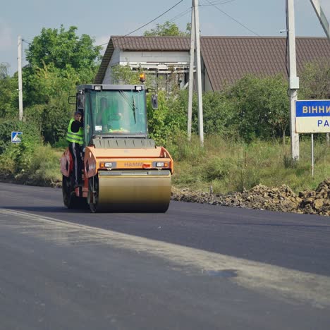 a steamroller rides through the new asphalt to level the surface. close-up