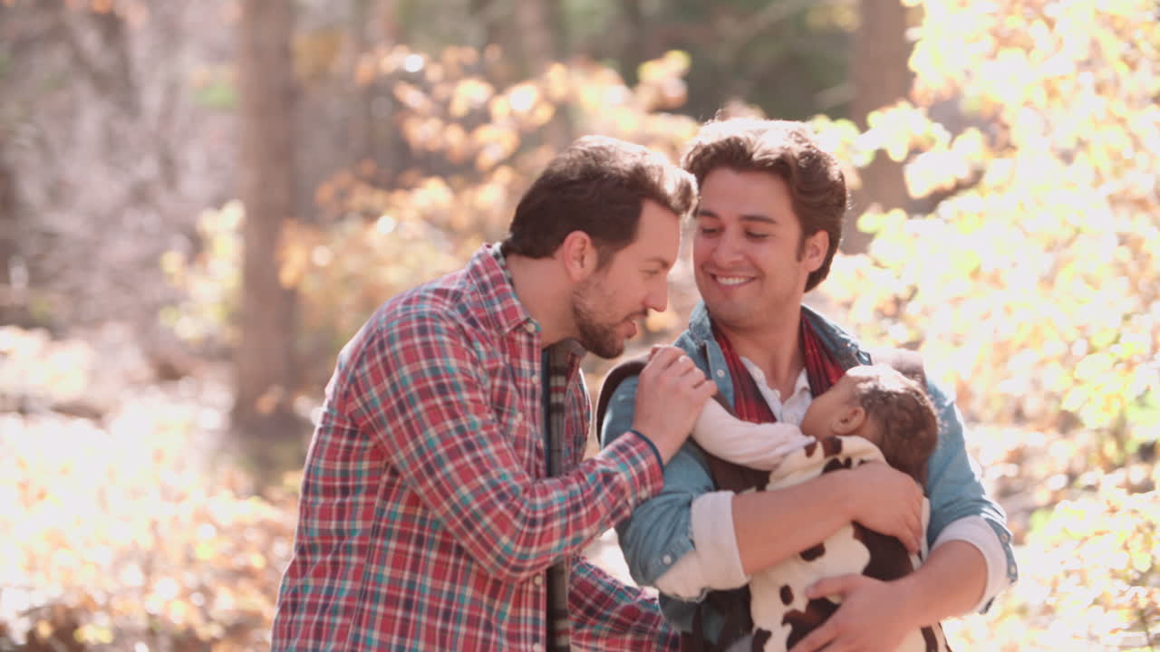 padres varones caminando en el bosque con el bebé en el sling, cintura hacia arriba
