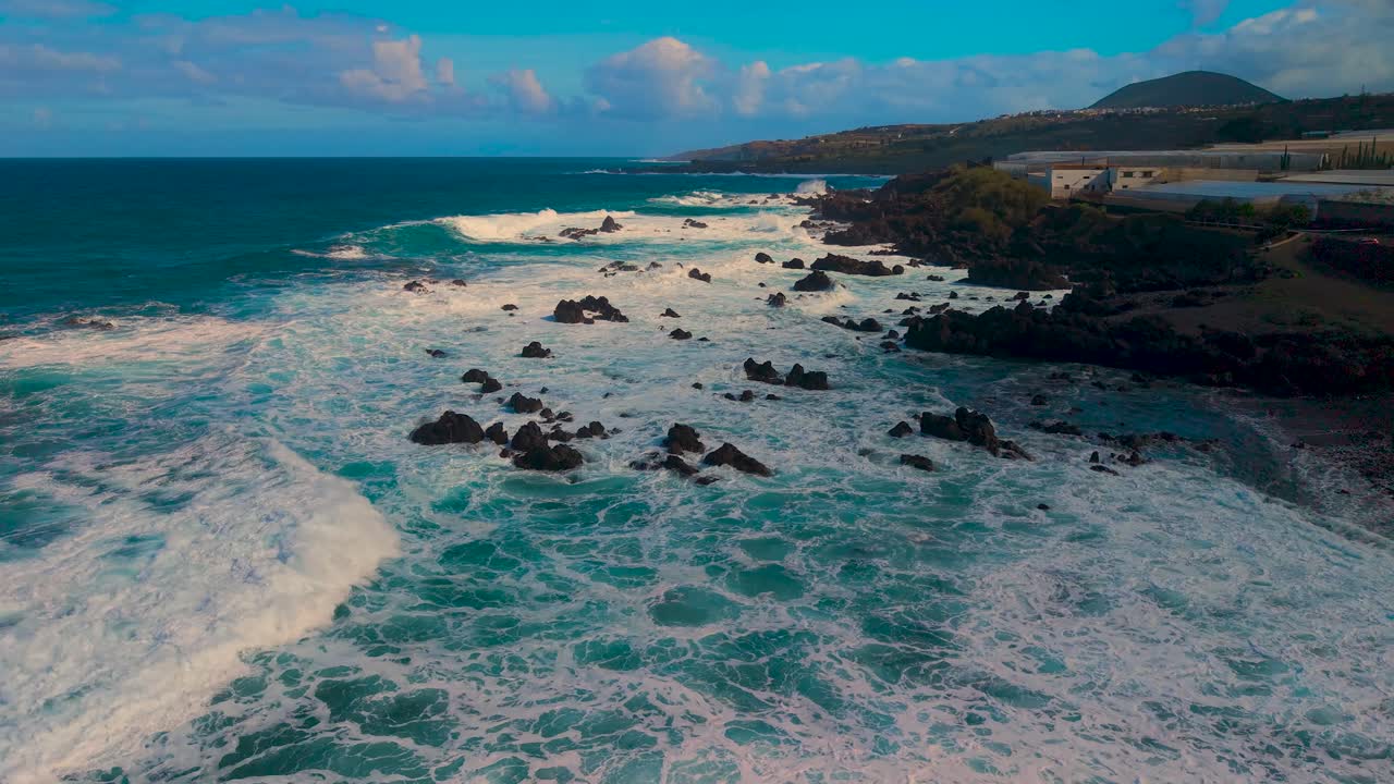 Aerial view of Tenerife's volcanic coast and rough sea in bright daylight