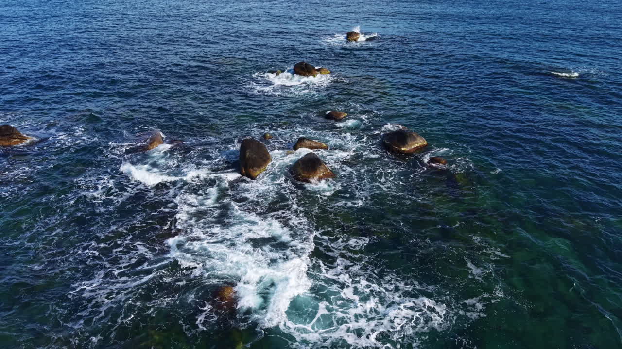 Onde che si infrangono su formazioni rocciose in un paesaggio costiero sereno in una luminosa giornata estiva vicino all'oceano