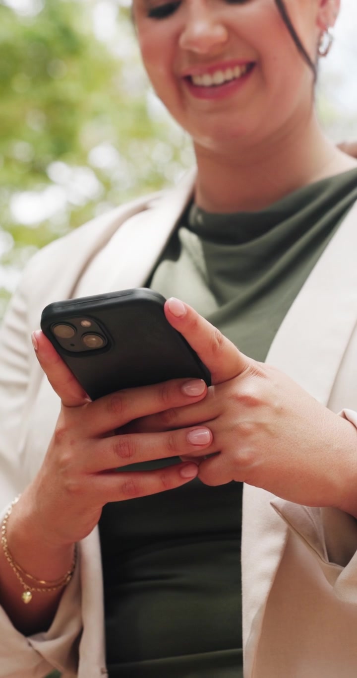 Donna sorridente che usa lo smartphone all'aperto