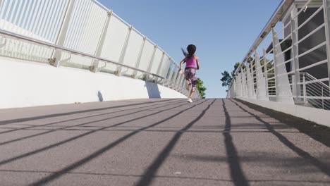 rear view of african american woman running on the city bridge