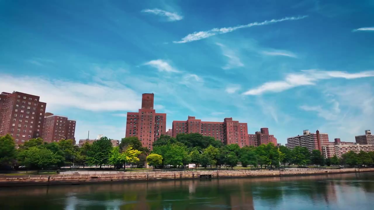Toma dinámica con rampa de velocidad desde una embarcación en movimiento pasando bajo el Puente de Roosevelt Island, revelando la estructura del puente levadizo de acero, la orilla del East River y el horizonte residencial en la ciudad de Nueva York