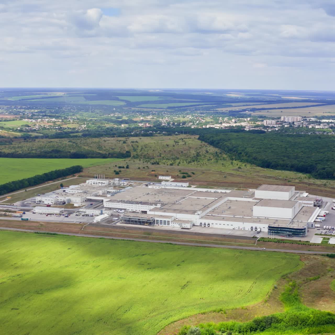 Manufacturing among beautiful nature in summer. Modern technology plant in natural environment. Panoramic view. View from above