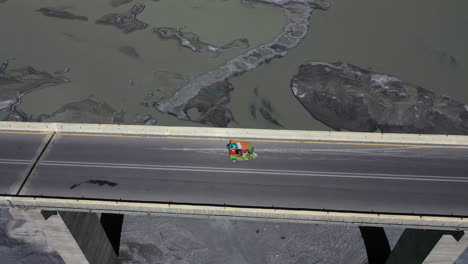 vista aérea de un auto rickshaw cruzando un puente de carretera de karakoram sobre el río hunza en pakistán