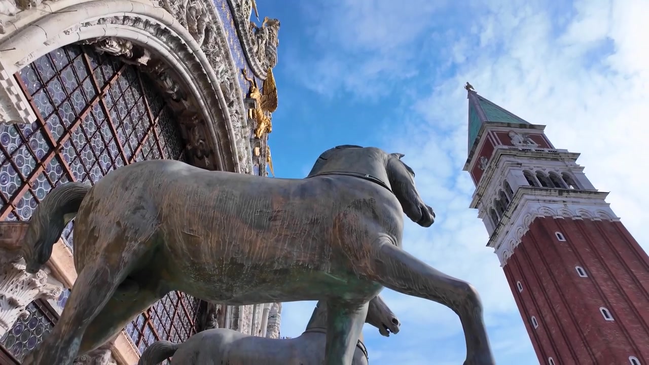 Angolazione cinematografica dall'alto che mostra gli iconici Cavalli della Basilica di San Marco e l'imponente Campanile in Piazza San Marco, Venezia, Italia