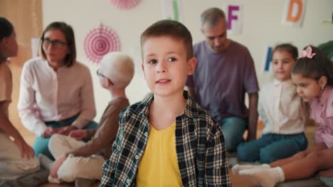 Portrait-of-a-little-boy-in-a-checkered-shirt-and-a-yellow-T-shirt-who-looks-at-the-camera-against-the-background-of-a-club-preparing-children-for-school.-The-little-boy-at-his-first-lesson-in-the-school-preparation-club