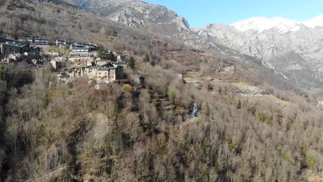 Aerial:-rack-railway-going-among-the-trees-and-into-the-woods,-climbing-a-mountain-with-a-small-village-in-the-background