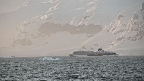 Big-cruise-expedition-ship-in-Antarctica-during-peak-season,-in-beautiful-light-with-ice-bergs-and-glaciers-around