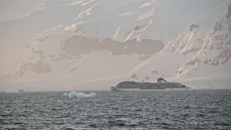 big cruise expedition ship in antarctica during peak season, in beautiful light with ice bergs and glaciers around