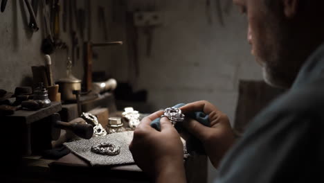 jeweler polishing silver jewelry in workshop