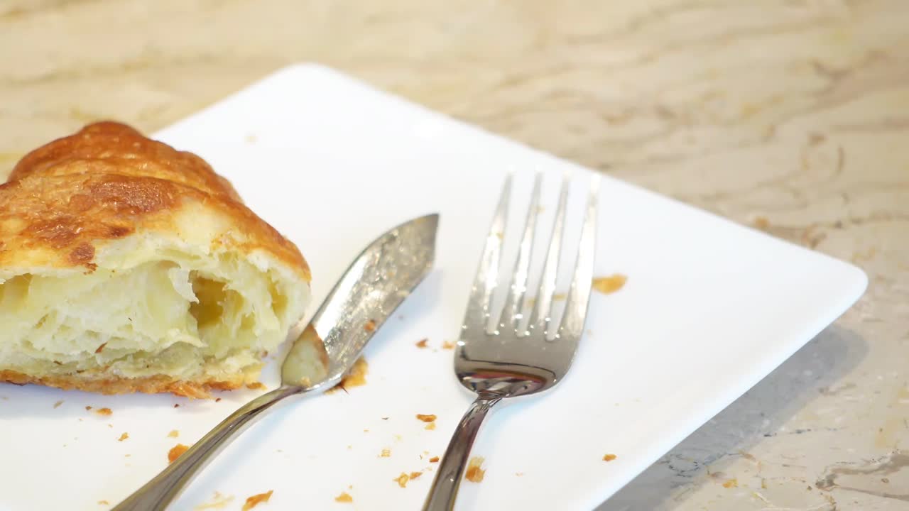 Částečně snědený croissant na talíři